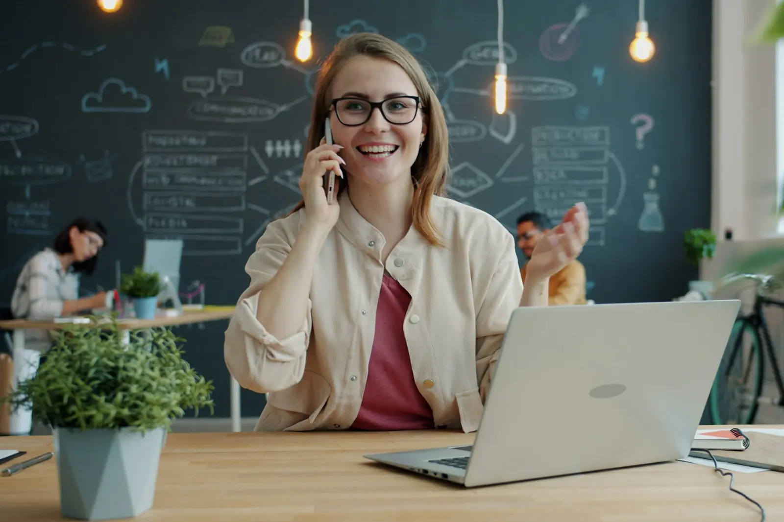 Medewerker belt met haar telefoon achter haar laptop op kantoor