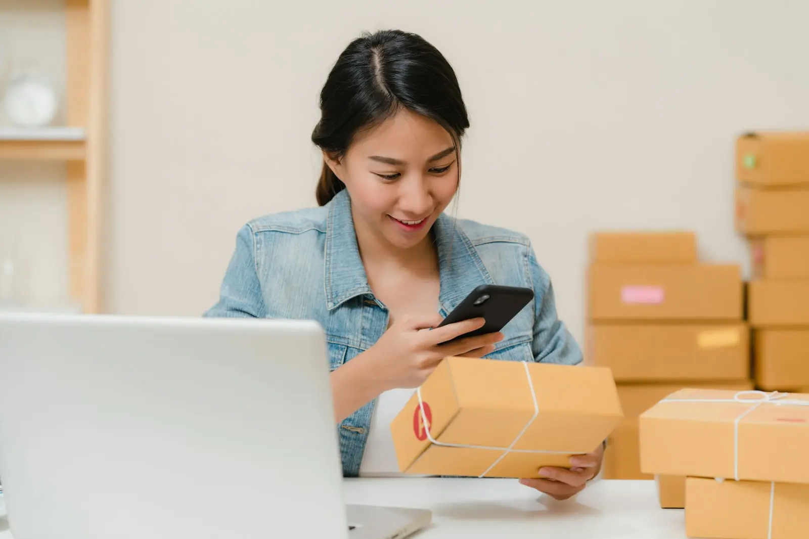 Webwinkelier pakt een bestelling in naast haar laptop